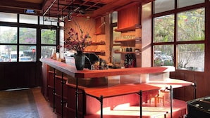 A bar area with a wooden counter, a vase with flowers, and a view of the outside through large windows. - The Pink Boutique Hotel (Cam Ly - Da Lat)