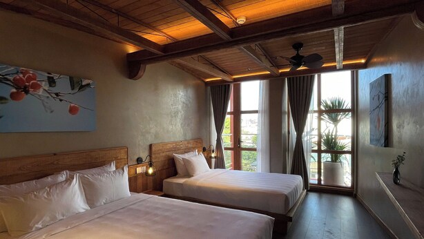 A hotel room with two beds, wooden ceiling beams, a large window with curtains, and a painting on the wall. - The Pink Boutique Hotel (Cam Ly - Da Lat)