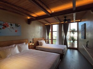 Habitación de hotel con dos camas, vigas de madera en el techo, un ventanal con cortinas y un cuadro en la pared.