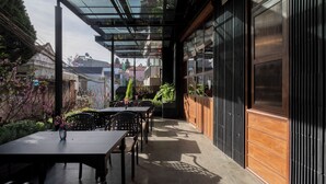 An outdoor patio with tables and chairs, a glass ceiling, and a view of the cityscape. - The Pink Boutique Hotel (Cam Ly - Da Lat)