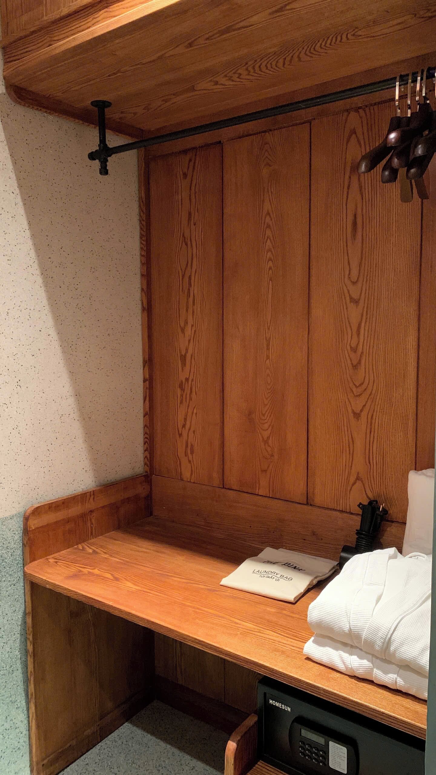 Un banco de madera con una bolsa de lavandería y toallas, una pared de madera y una lámpara en el techo.