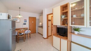 Une cuisine compacte comprenant une table à manger, des chaises, un réfrigérateur, un four à micro-ondes et un téléviseur.