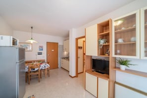 Une cuisine compacte comprenant une table à manger, des chaises, un réfrigérateur, un four à micro-ondes et un téléviseur.