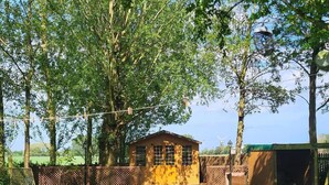 A fenced backyard with a small yellow building, a wooden deck, and a green lawn. - Three Farthings Bed & Breakfast, a quiet and peaceful countryside location. (Driffield)