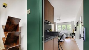 A modern kitchen with wooden cabinets, a black countertop, and a dining area with a table and chairs. - Modern "Green Suites" residence - Meudon/Vélizy (Meudon)