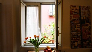A window with a view of a balcony, a vase with flowers, and a fruit bowl on a table. - La Casa di Apollo (Naples)