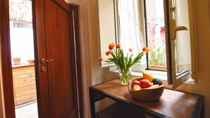 A wooden door, a window with a view of a balcony, and a table with a vase of tulips and a bowl of fruit. - La Casa di Apollo (Naples)