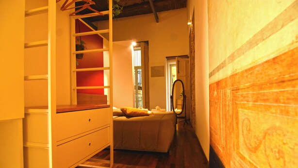 A narrow hallway with a bed, a ladder, and a wooden floor. - La Casa di Apollo (Naples)