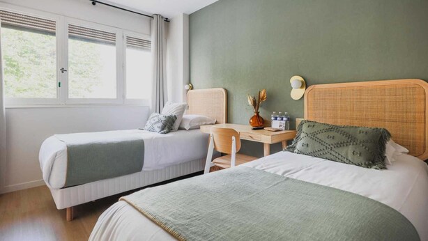 Un dormitorio con dos camas, un escritorio y una ventana.