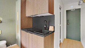 A compact kitchen with a black countertop, wooden cabinets, and a modern faucet. - Modern "Green Suites" residence - Meudon/Vélizy (Meudon)