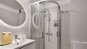 Une salle de bain moderne avec une douche à parois de verre, un lavabo avec un miroir et des toilettes.