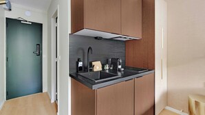 A modern kitchen with a black countertop, wooden cabinets, and a built-in range hood. - Modern "Green Suites" residence - Meudon/Vélizy (Meudon)