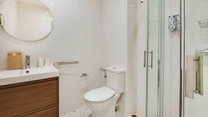 A modern bathroom with a white toilet, a round mirror, and a glass shower enclosure. - Modern "Green Suites" residence - Meudon/Vélizy (Meudon)