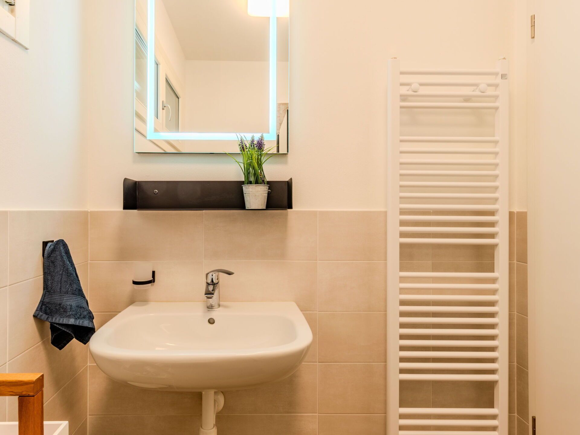 A bathroom with a sink, mirror, towel rack, and a white towel.