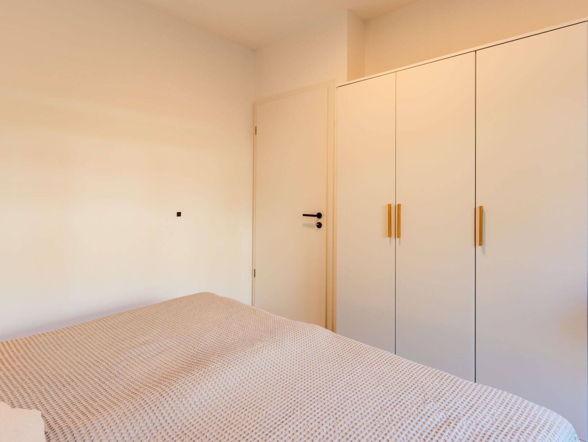 A bedroom with a bed, a wardrobe, and a door.