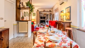 A dining area with a table set for four, a radiator, a bookshelf, and a red chair.