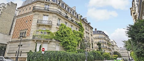 Un edificio histórico con arquitectura ornamentada, una señal de ‘prohibido el acceso’ y un coche verde estacionado en la calle.