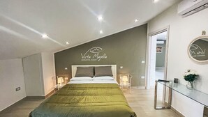 A modern bedroom with a bed, bedside tables, a mirror, and a wall sign.