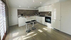 A modern kitchen with white cabinetry, a built-in oven, and a central island with stools.
