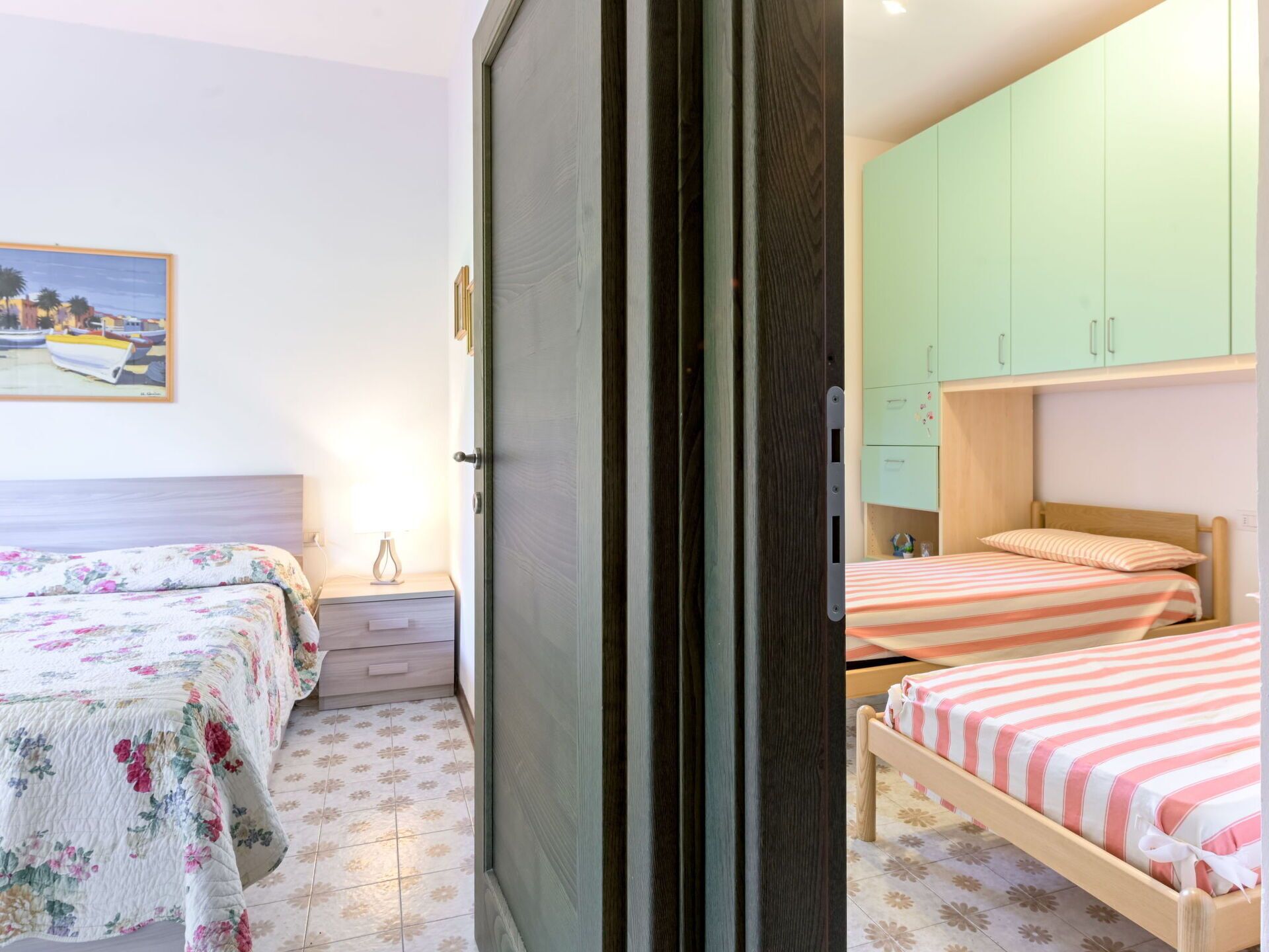 Een slaapkamer met twee bedden, een nachtkastje, een dressoir en een groene garderobe.