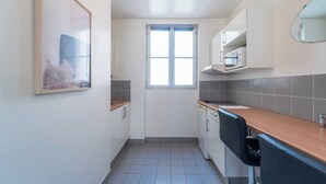Una cocina compacta con ventana, armarios blancos y encimera.