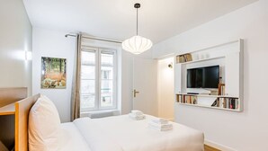 Quarto de hotel com uma cama, uma televisão e uma estante de livros.