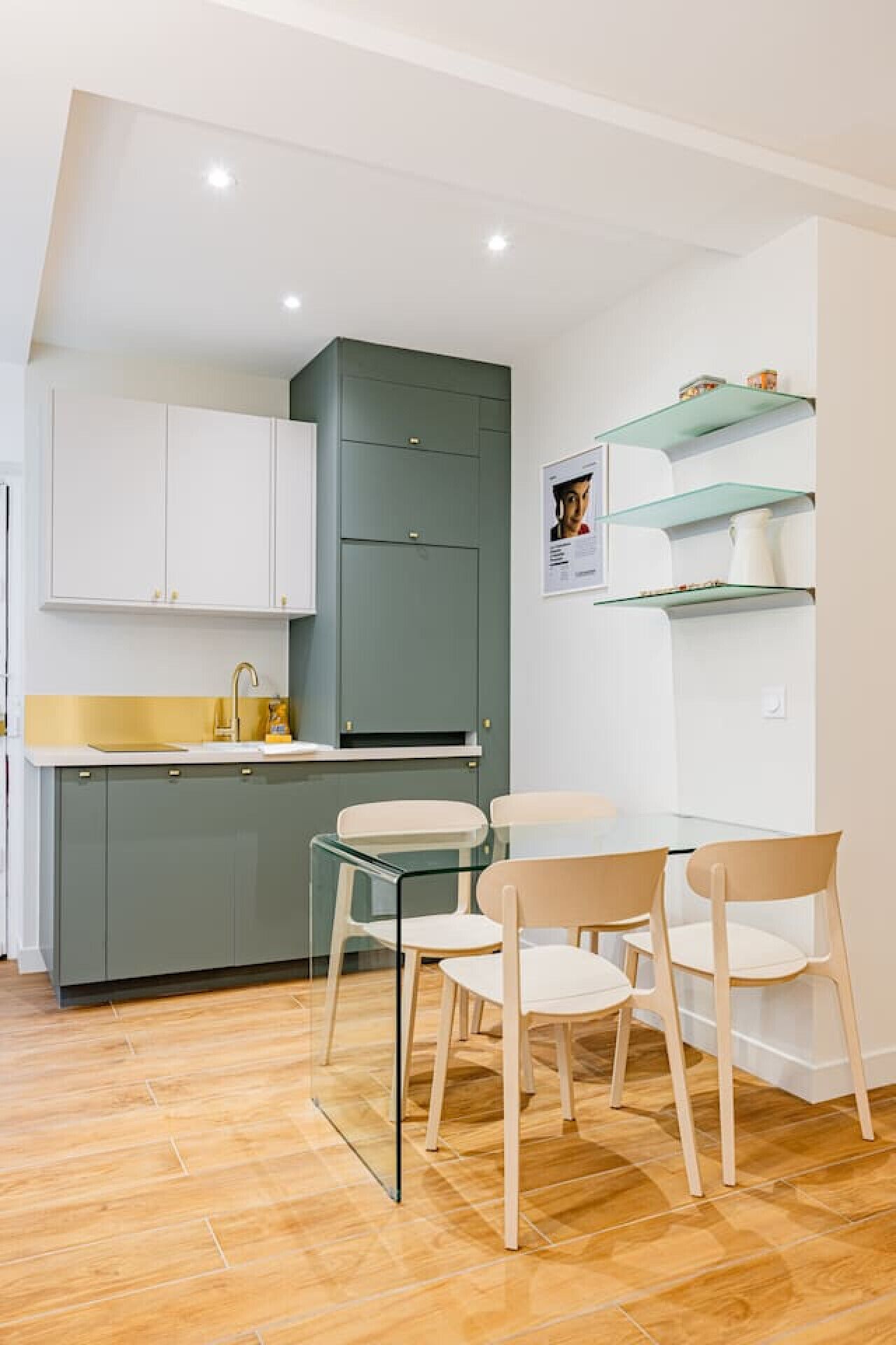 A compact kitchen with a sink, cabinets, and a dining area with chairs and a table.