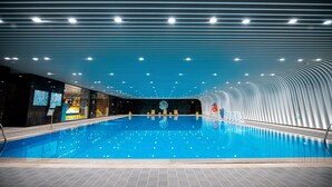 Une piscine intérieure au design moderne, dotée d’un plafond incurvé et d’un éclairage lumineux.