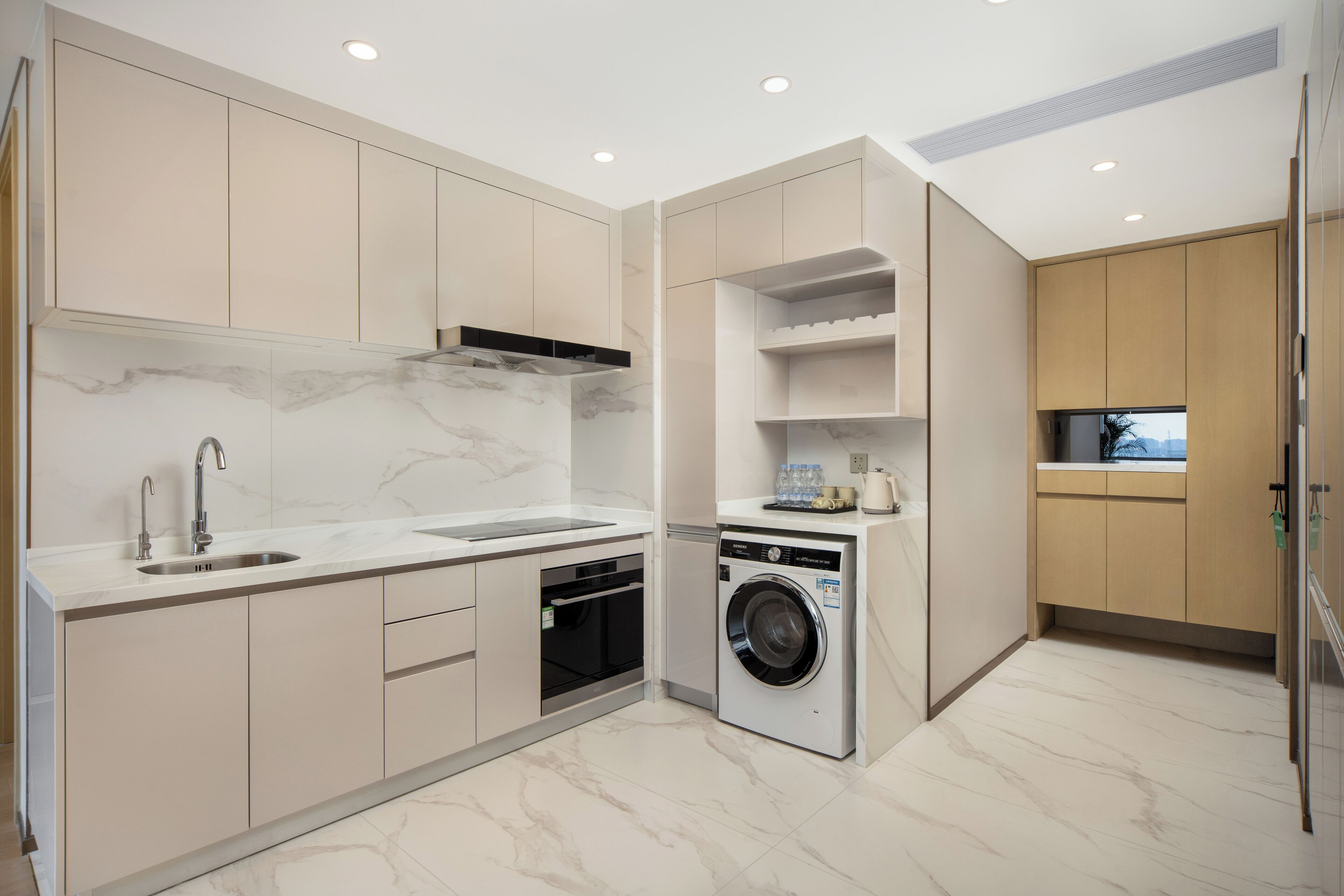 A modern kitchen with a marble countertop, built-in oven, and a washing machine.
