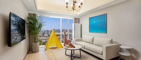 Un salon moderne avec un canapé, une petite table basse, une tente de jeu jaune et une vue sur la ville à travers de grandes fenêtres.