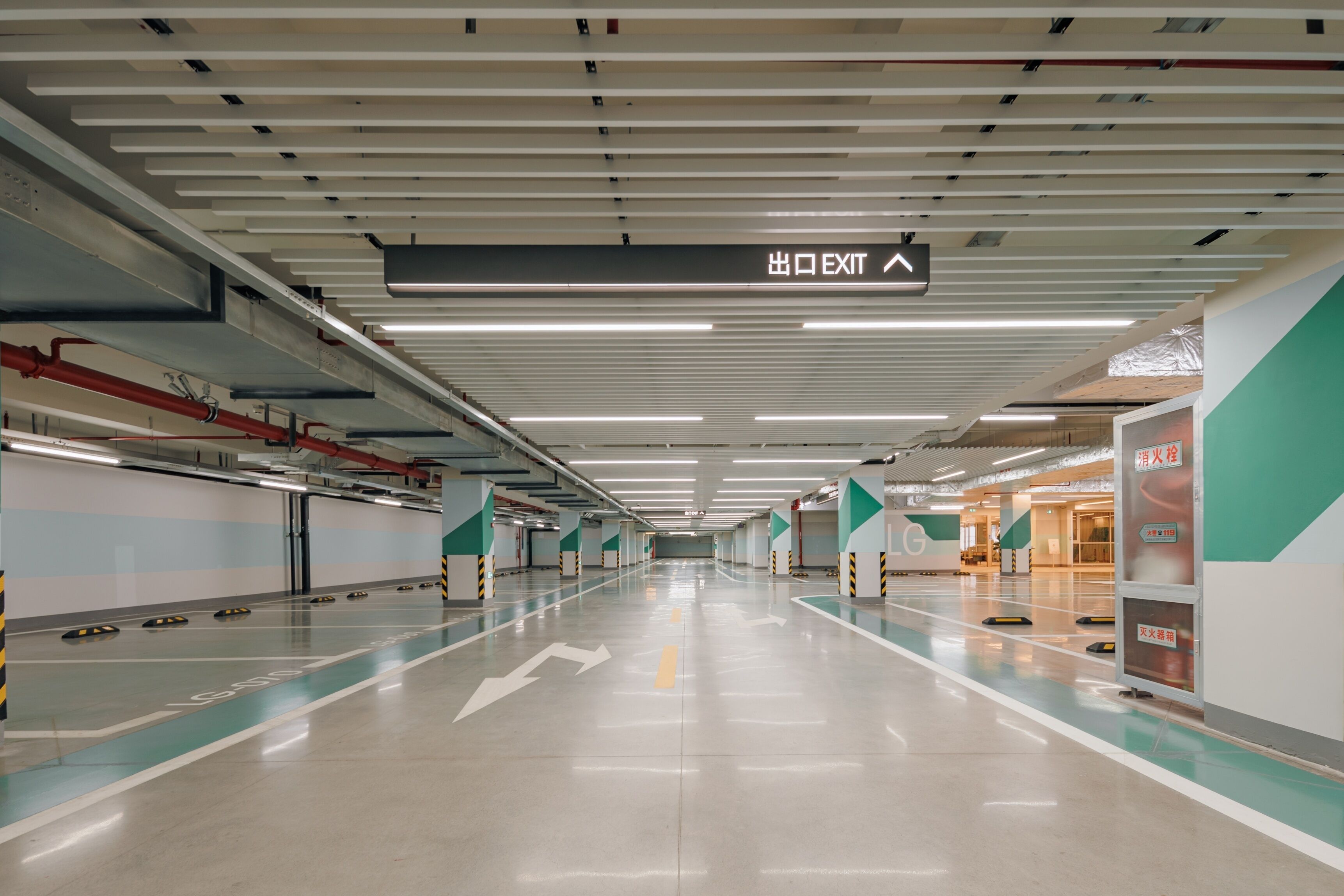 Un aparcamiento subterráneo amplio y bien iluminado, con señalización direccional clara, incluyendo un letrero de salida.
