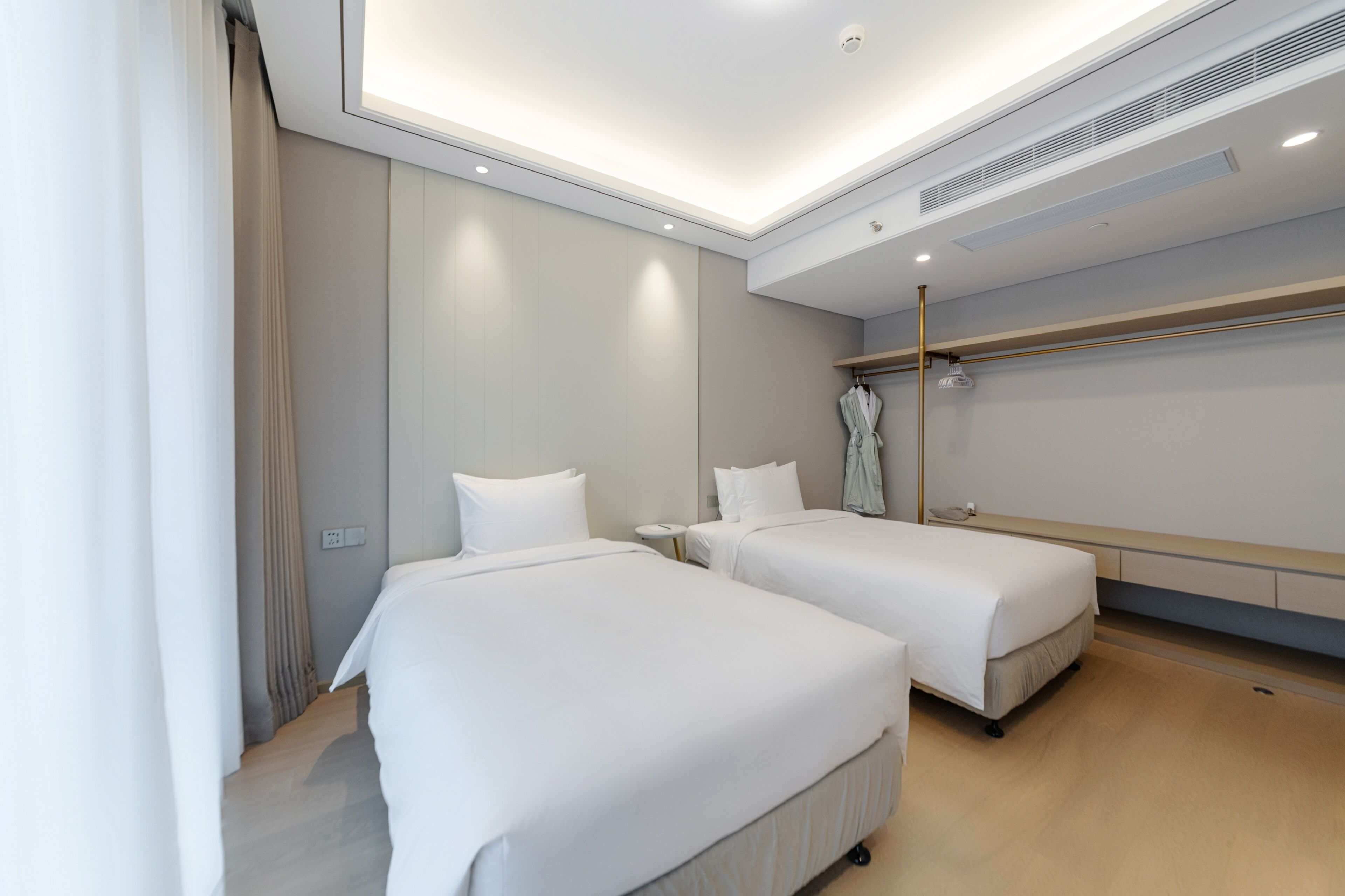 Une chambre d’hôtel avec deux lits, une armoire, un miroir et un luminaire au plafond.