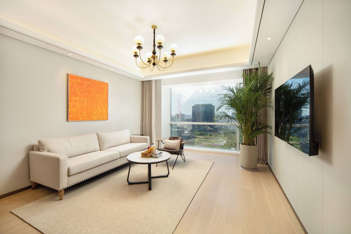Ein modernes Wohnzimmer mit Sofa, Couchtisch und einem großen Fenster mit Blick auf die Stadt.