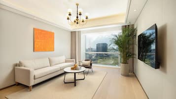 A modern living room with a sofa, coffee table, and a large window offering a city view.