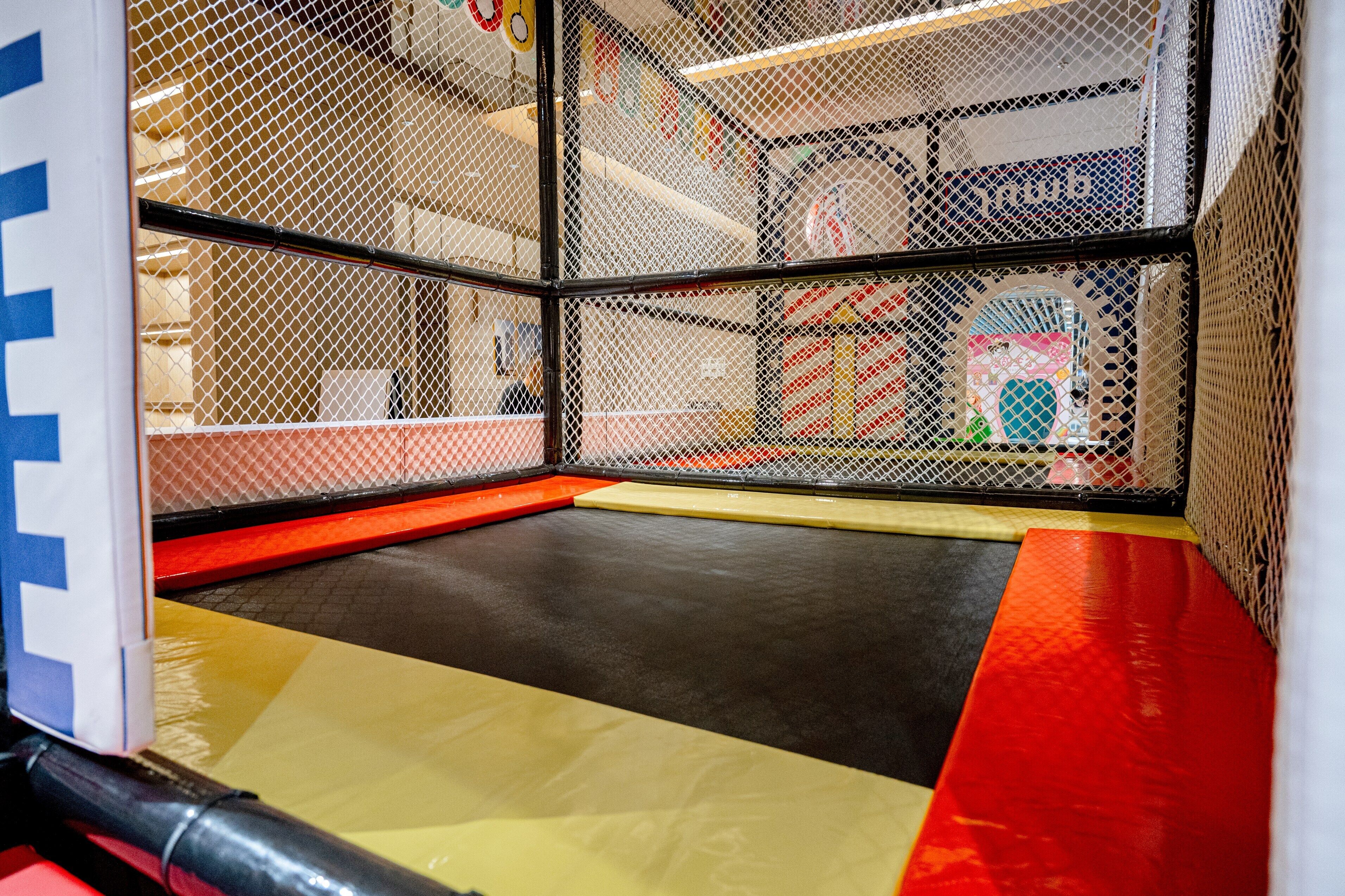 Ein Indoor-Spielbereich mit gepolstertem Boden und Sicherheitsnetzen.