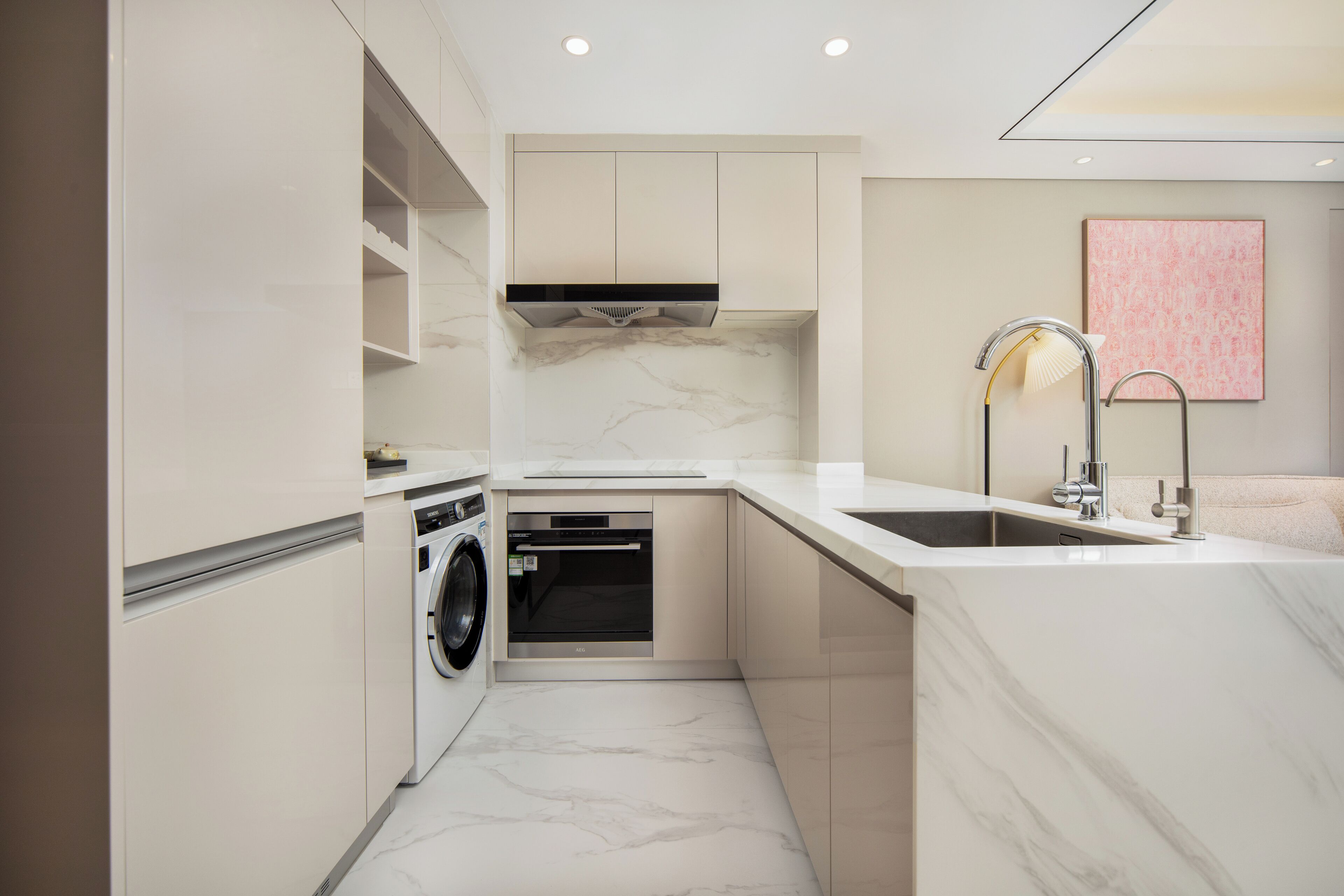 Une cuisine compacte dotée d’appareils électroménagers intégrés, d’un pare-feu en marbre et d’un design minimaliste.