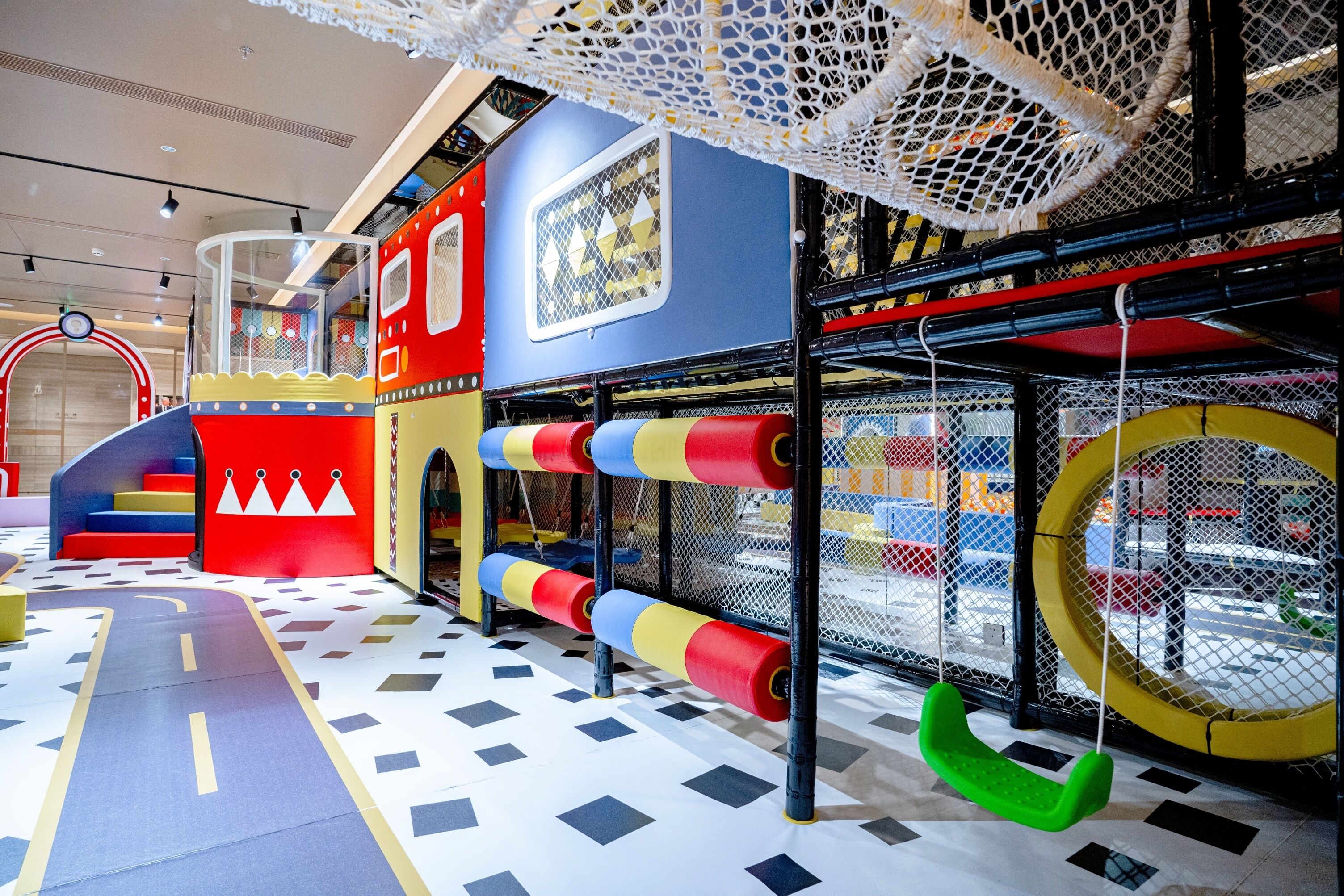 Een kinderspeelplaats met kleurrijke speeltoestellen, een klimnet en een glijbaan.
