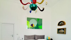 A bedroom with a bed, a green nightstand, a white door, and a colorful chandelier. - Gorgeous detached house with sea view in Amalfi "Penelope 13 Suite (Amalfi)