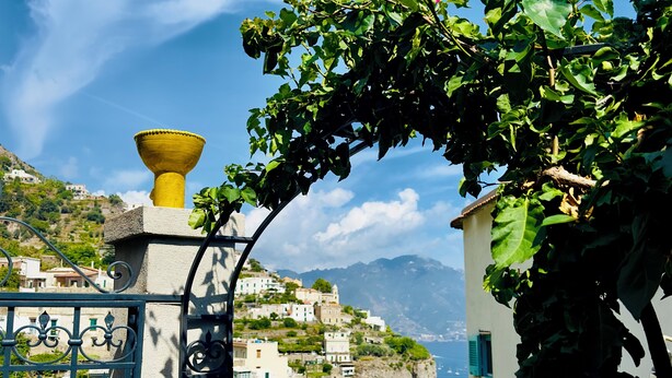 A coastal village with traditional architecture, a gate with decorative metalwork, and a view of the sea and mountains. - Gorgeous detached house with sea view in Amalfi "Penelope 13 Suite (Amalfi)