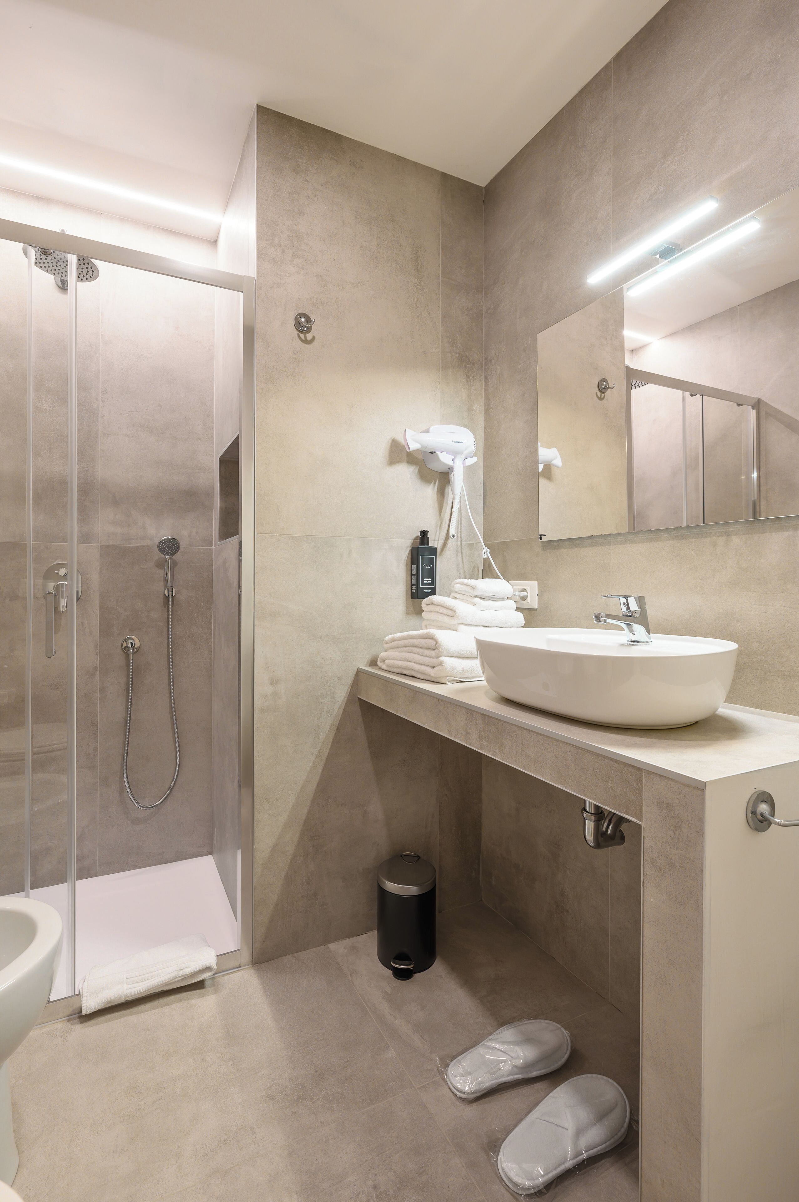 A modern bathroom with a glass-enclosed shower, a sink with a mirror, and a towel rack.