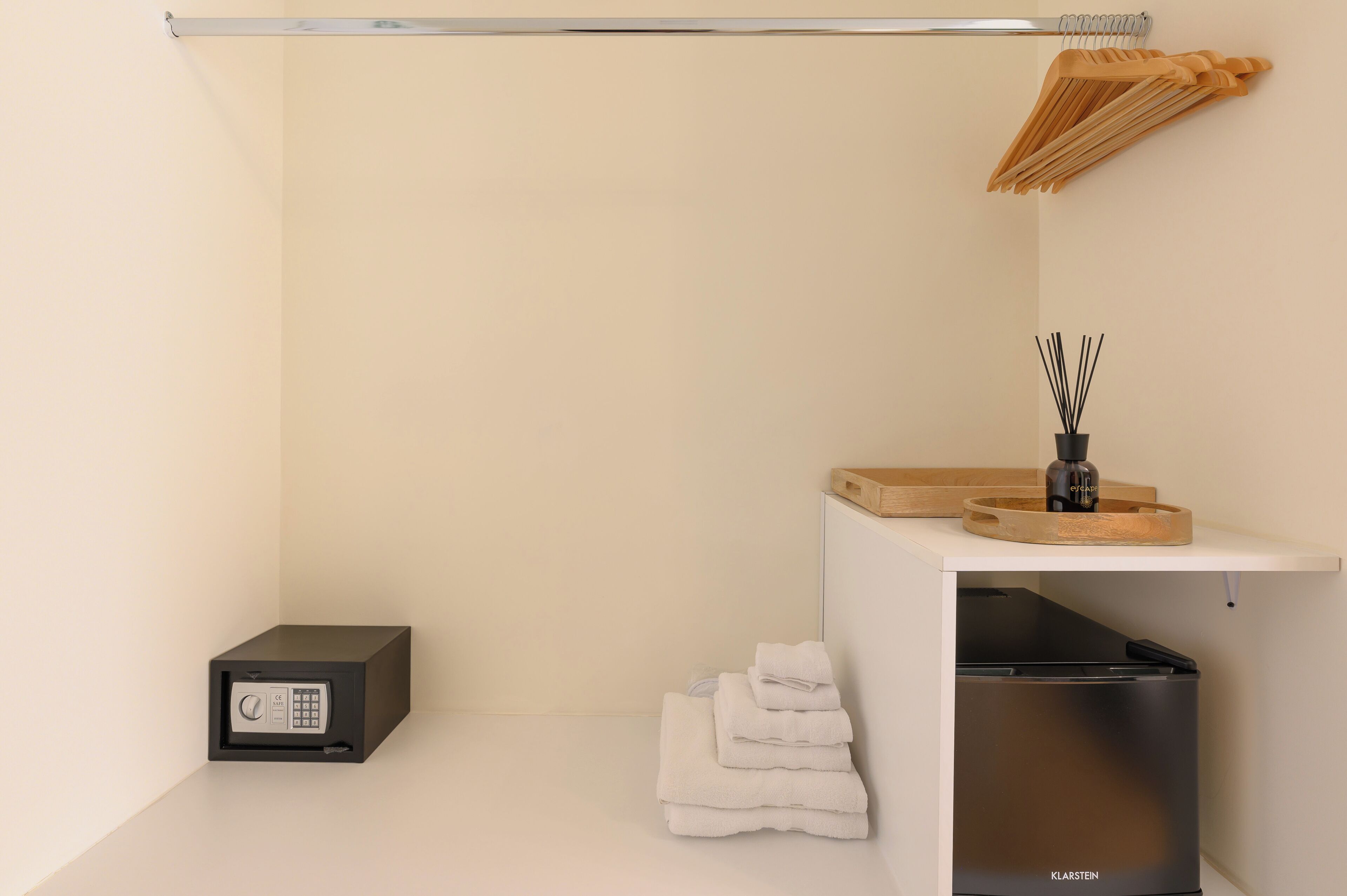 A minimalist bathroom with a black safe, a towel stack, and a wooden towel rack.