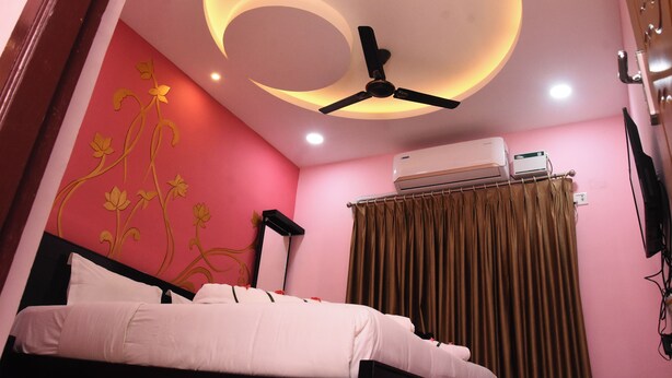 A bedroom with a bed, a ceiling fan, an air conditioning unit, and a curtain. - Uma Residency (Mayiladuthurai)