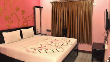 A hotel room with a bed, a nightstand, a TV, and a window with curtains.