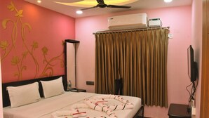 A hotel room with a bed, a ceiling fan, an air conditioning unit, a television, and a curtain. - Uma Residency (Mayiladuthurai)