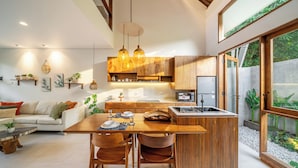 A modern kitchen with wooden cabinets, a central island, and pendant lighting. - Chindaga Villa Canggu (Canggu)