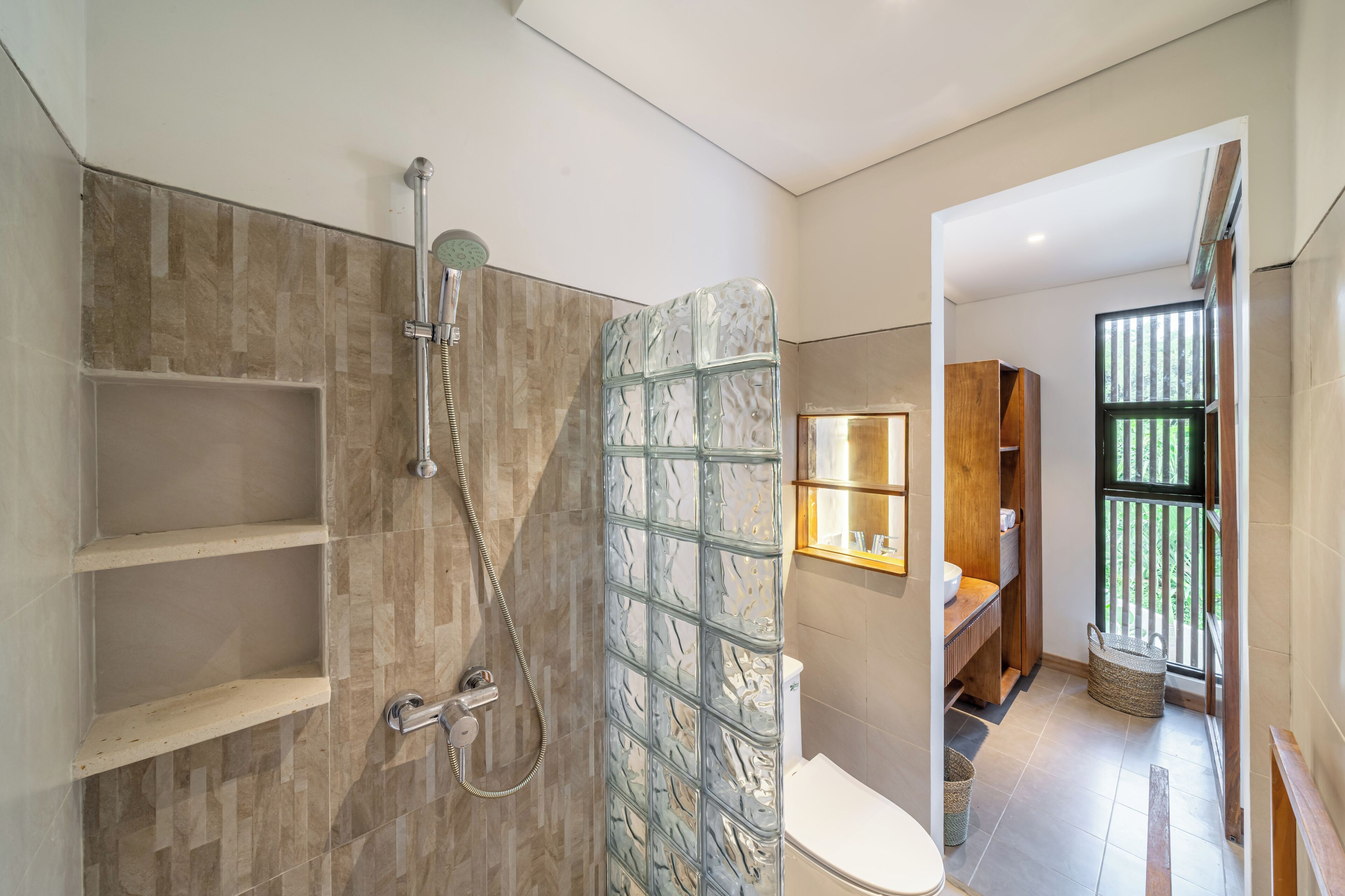 A modern bathroom with a glass shower enclosure, a toilet, and a sink area.