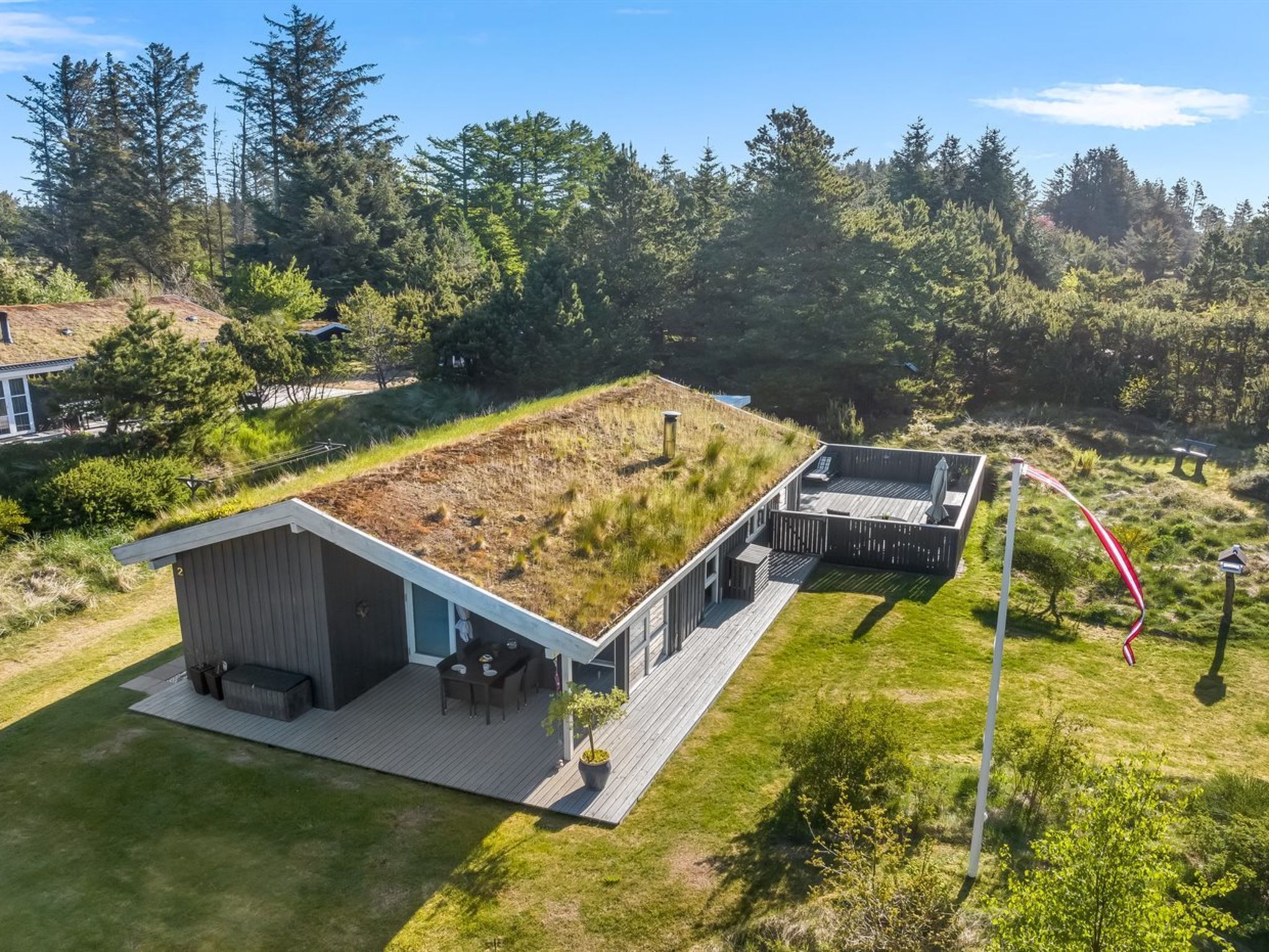 Ein modernes Haus mit flachem Gründach, einer Terrasse und einer Terrassenanlage.