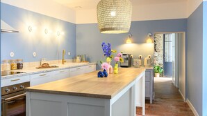A modern kitchen with a wooden island, stainless steel appliances, and a hanging light fixture.