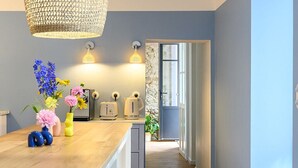 A kitchen with a wooden island, hanging woven light fixture, and a stone wall.