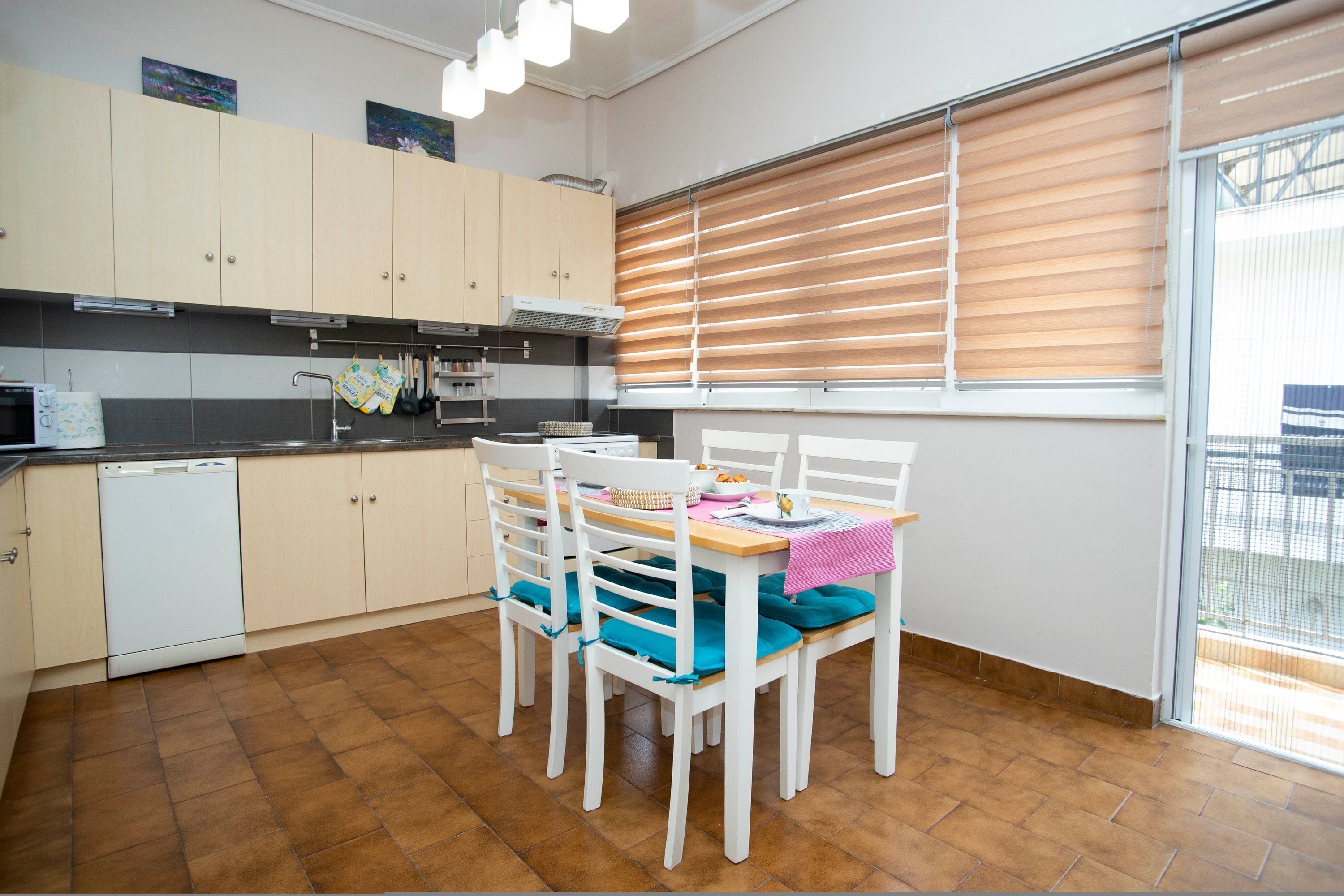 A kitchen with white cabinets, a dishwasher, and a dining table with chairs.